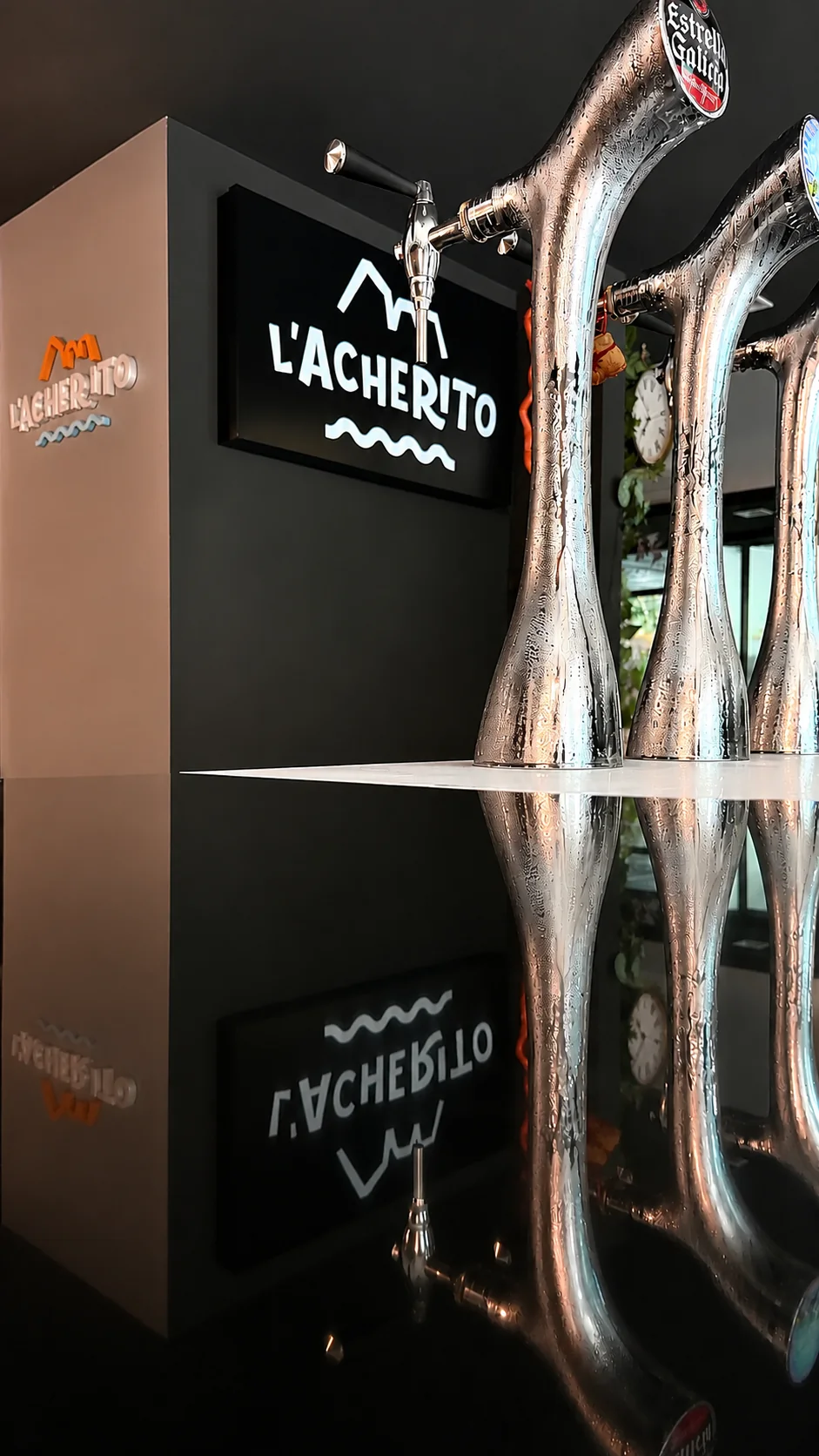 Detalle del logo neón de L'Acherito con grifo de vermut reflejado